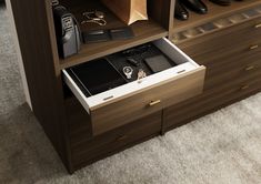 an open drawer in a wooden cabinet filled with shoes and other items on top of carpeted flooring