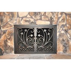 an iron gate is shown in front of a stone fireplace mantel with decorative designs on it