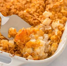 a casserole dish filled with macaroni and cheese topped with a serving spoon