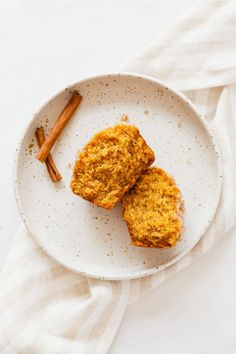 two muffins on a white plate with cinnamon sticks