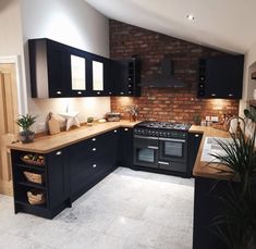 a kitchen with black cabinets and wooden counter tops is shown in this image, there is a potted plant next to the stove