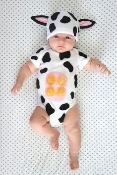 a baby wearing a cow costume laying on top of a white sheet with the words baby cow costume written across it