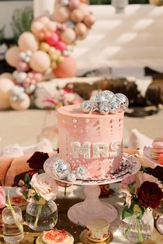 a pink cake sitting on top of a table next to other cakes and desserts