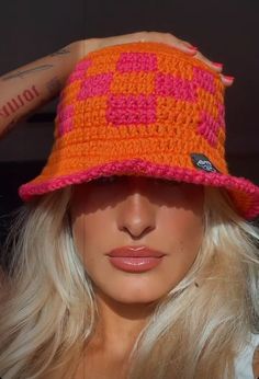 a woman wearing an orange and pink crocheted hat on top of her head