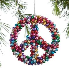 a peace sign ornament hanging from a pine tree with colorful beads on it