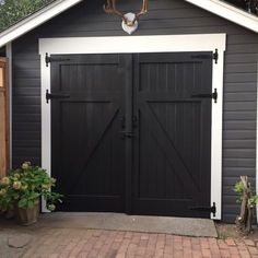 a black garage with two double doors and a deer head on the top of it