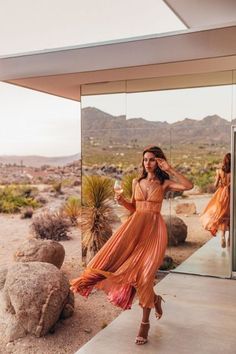 a woman in an orange dress is standing outside