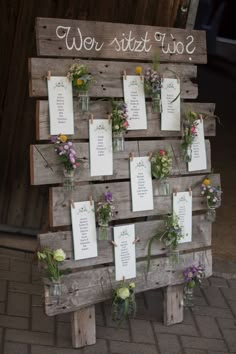 a wooden sign with flowers on it and seating cards attached to the back of it