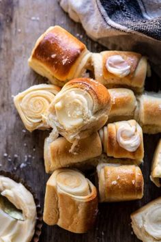 several rolls with butter on them sitting on a wooden table next to some cupcakes