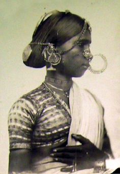 an old black and white photo of a woman with large hoops on her head