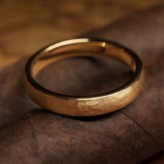 a gold wedding ring sitting on top of a piece of leather