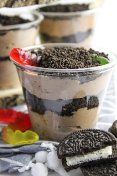 an oreo cookie ice cream dessert in a plastic cup on a table next to cookies