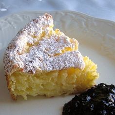 a piece of cake on a plate next to a small black pastry with powdered sugar