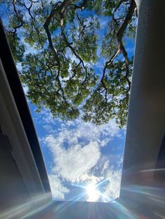 the sun shines brightly through some trees in front of a blue sky with white clouds