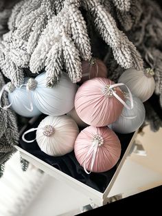 a bunch of ornaments that are sitting in a box on a table next to a christmas tree