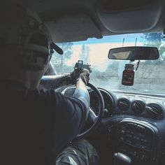 a man driving a car with his hand on the steering wheel