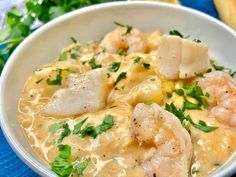 a white bowl filled with shrimp and grits on top of a blue table cloth