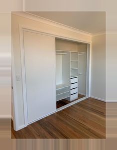 an empty bedroom with white walls and wooden flooring is seen in this image from the doorway