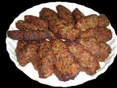 a white plate topped with meat patties on top of a black table next to a fork