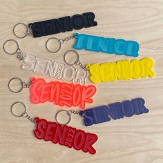 four different colored key chains with the words senior, senior, senior and senior on them