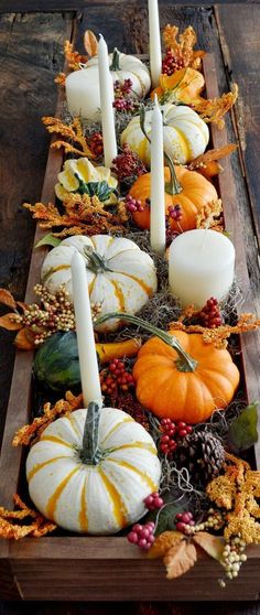 a wooden table topped with lots of pumpkins and candles