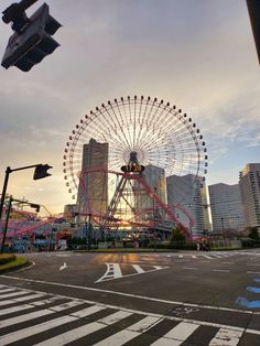 a ferris wheel in the middle of an empty parking lot with buildings in the background