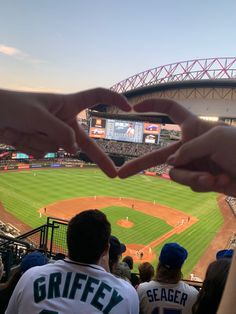 two hands making a heart shape at a baseball game