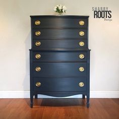 a black dresser with gold handles and knobs on the bottom drawer, against a white wall