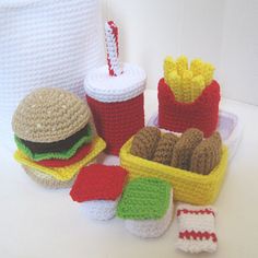 crocheted food items displayed on white surface with red and green striped straws