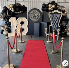 a red carpet is on the ground next to some chairs and poles with rope barriers around them