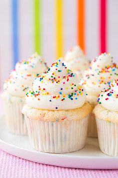 cupcakes with white frosting and sprinkles on a plate