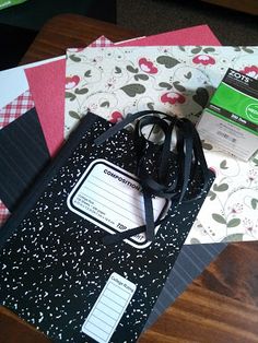 an assortment of stationery items on top of a wooden table, including notebooks and papers