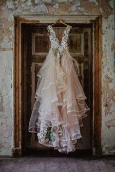 a wedding dress hanging on a door in an old building