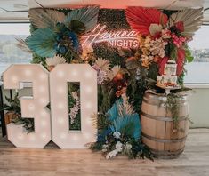 an illuminated sign that says 30th next to a barrel with flowers and greenery on it