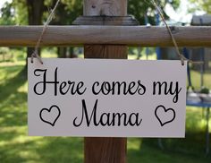 there is a sign that says here comes my mama hanging on a fence post in the grass