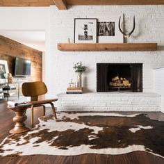 a living room with a fireplace and cow hide rug