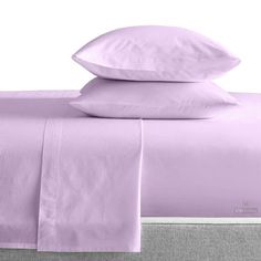 the sheets and pillow cases are made up with lavender colored linens on top of each other