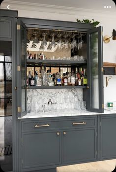 a bar with wine glasses and liquor bottles on it's shelves in a kitchen