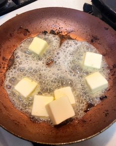 four pieces of cheese are being cooked in a frying pan on the stove top