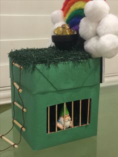 a green house with a potted plant on top and a rainbow in the window