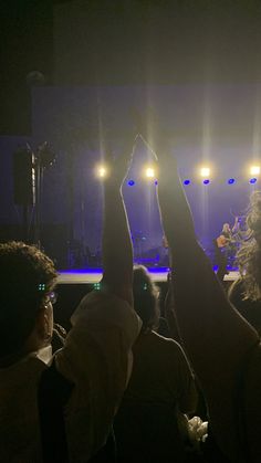 people raising their hands in the air at a concert