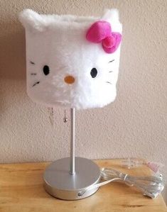 a white hello kitty lamp with a pink bow on it's head sitting on a table