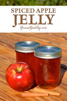 two jars filled with apple jelly sitting on top of a wooden table next to an apple