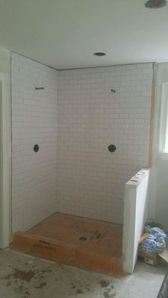 a bathroom being remodeled with white tiles and no shower curtain