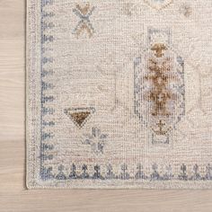 a beige rug with blue and white designs on the bottom, sitting on top of a wooden floor