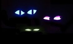 two glowing eyes in the dark, one is purple and one is blue with white