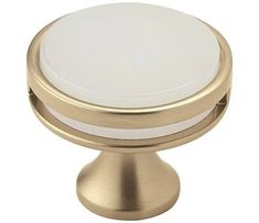 an image of a white knob on a gold plated cabinet door or drawer handle