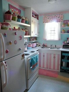 a kitchen with pink and blue walls, white appliances and cupcakes on the shelves