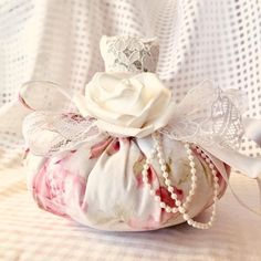 a white rose in a fabric bag with lace on the top and ribbon around it