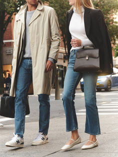 a man and woman are walking down the street with their handbags in each other's pockets